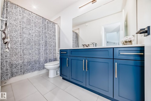 Bathroom featuring a dual-sink vanity with blue cabinetry, white countertop, and brushed nickel hardware - 46 1304 Rutherford Road, Edmonton, AB - Indoor Photo Showing Bathroom