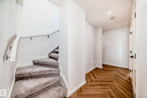 Staircase featuring grey carpeted treads, white handrail, and brushed nickel supports - 46 1304 Rutherford Road, Edmonton, AB - Indoor Photo Showing Other Room