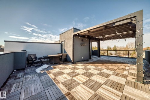 Expansive rooftop deck featuring varied-tone wood-finish decking, a built-in pergola with string lighting, and glass panel railings - 46 1304 Rutherford Road, Edmonton, AB - Outdoor With Deck Patio Veranda With Exterior