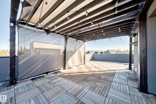 Rooftop patio featuring a slatted wood-finish pergola, string lighting, and wood-finish tile flooring - 46 1304 Rutherford Road, Edmonton, AB - 