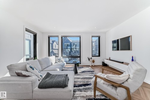 Bright living area featuring expansive windows, recessed lighting, and herringbone wood-finish flooring - 46 1304 Rutherford Road, Edmonton, AB - Indoor Photo Showing Living Room