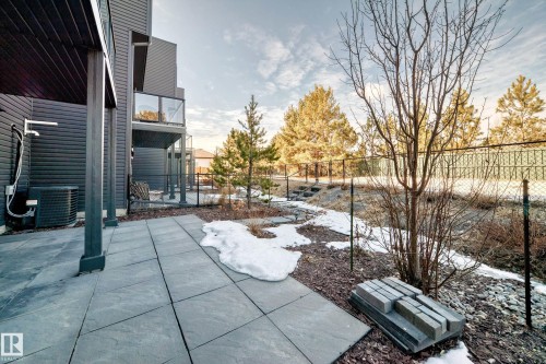 Ground-level patio constructed with large format pavers, featuring a dark exterior facade and an overhead covered space - 46 1304 Rutherford Road, Edmonton, AB - Outdoor