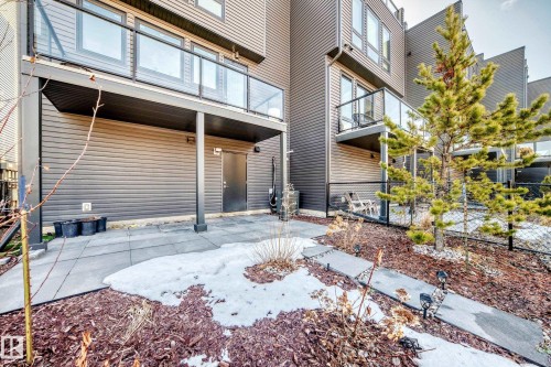 Rear patio area featuring concrete paving, a covered section, and a privacy fence - 46 1304 Rutherford Road, Edmonton, AB - Outdoor With Exterior