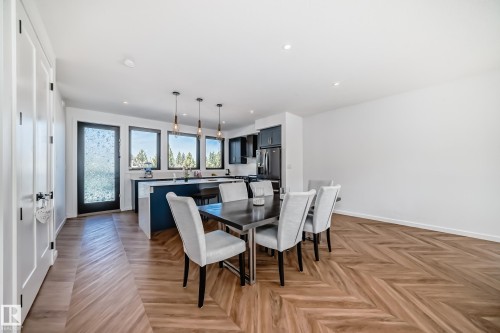 Open-concept living area featuring herringbone wood-finish flooring, recessed lighting, and a kitchen island with pendant lighting - 46 1304 Rutherford Road, Edmonton, AB - Indoor Photo Showing Dining Room