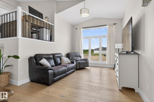 Living area featuring wood-finish flooring, a contemporary chandelier, and a large window - 4204 55Av, Lamont, AB 