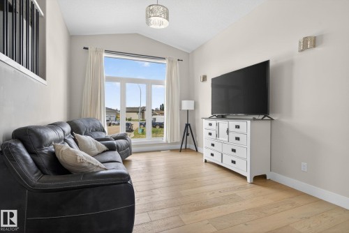 Living area featuring vaulted ceilings, light wood-finish flooring, and a large multi-pane window - 4204 55Av, Lamont, AB 