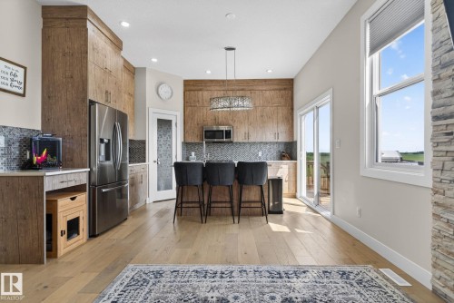 Modern kitchen featuring light wood-finish cabinetry, stainless steel appliances, and a mosaic tile backsplash - 4204 55Av, Lamont, AB 