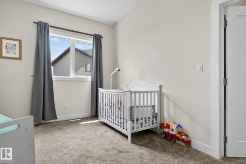 Room featuring a neutral color palette, grey carpeting, a large window with white trim, and a white interior door - 4204 55Av, Lamont, AB 