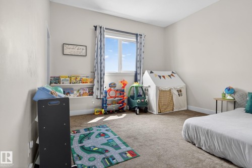 Spacious room featuring neutral carpeting, a large window with natural light, and built-in shelving - 4204 55Av, Lamont, AB 