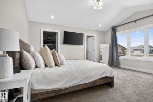 Vaulted ceiling bedroom featuring plush carpet flooring, recessed lighting, and a large multi-pane window with architectural trim - 4204 55Av, Lamont, AB 