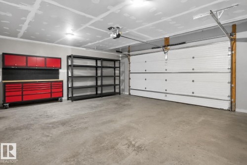 Spacious garage with a sectional overhead door, automatic opener, and a durable concrete floor - 4204 55Av, Lamont, AB 