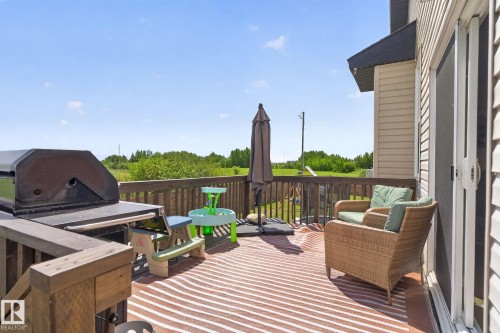 Spacious outdoor deck featuring wooden railing, a sliding patio door, and vinyl siding on the exterior - 4204 55Av, Lamont, AB 