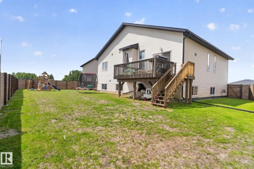 Expansive backyard featuring a wood deck with stairs, a cream-colored siding exterior, and a privacy fence - 4204 55Av, Lamont, AB 