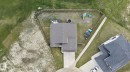Gray shingle roof, concrete driveway, concrete sidewalk, wood fence enclosure, and surrounding green space - 4204 55Av, Lamont, AB 