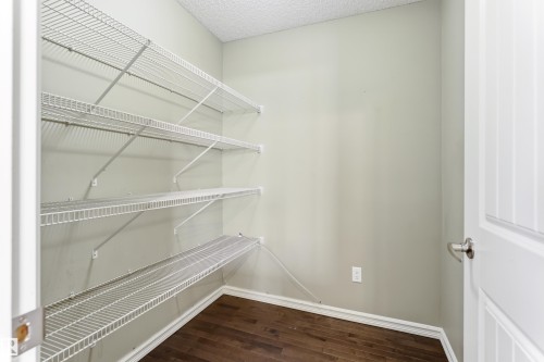 Walk-in closet featuring multiple tiers of white wire shelving, wood-finish flooring, and light-toned wall paint - 8204 180 Avenue, Edmonton, AB 