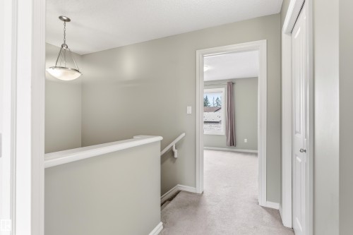 Upper-level hallway with neutral carpeting, painted walls, and white trim - 8204 180 Avenue, Edmonton, AB 