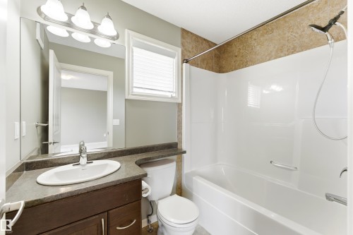 Bathroom featuring a white bathtub and shower combination with a textured tile surround - 8204 180 Avenue, Edmonton, AB 