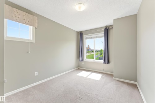 Neutral-toned interior room with light gray walls, white trim, and light-colored carpet flooring - 8204 180 Avenue, Edmonton, AB 