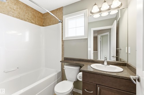 Bathroom featuring a built-in tub with a white surround and a textured tiled shower wall - 8204 180 Avenue, Edmonton, AB 