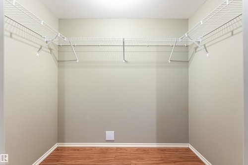 Spacious closet featuring an L-shaped wire shelving system, light gray walls, white baseboards, and wood-finish flooring - 8204 180 Avenue, Edmonton, AB 