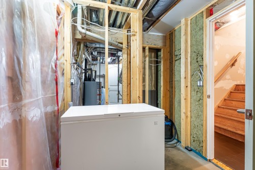 Unfinished basement featuring exposed wood framing, ceiling joists, and visible utility infrastructure, including a water heater - 8204 180 Avenue, Edmonton, AB 
