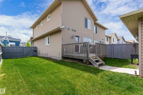 Rear exterior featuring a wooden deck with steps, a fenced yard, and beige horizontal siding - 8204 180 Avenue, Edmonton, AB 
