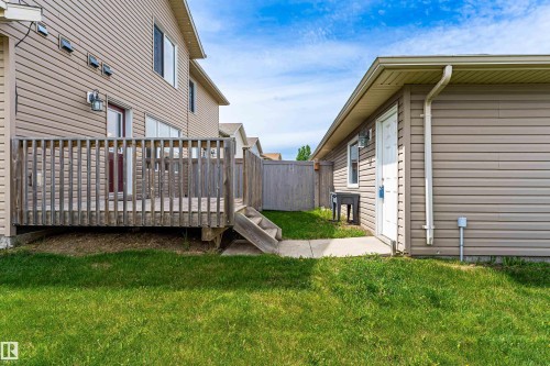 Private backyard featuring a wood deck, concrete pathway, and green lawn - 8204 180 Avenue, Edmonton, AB 