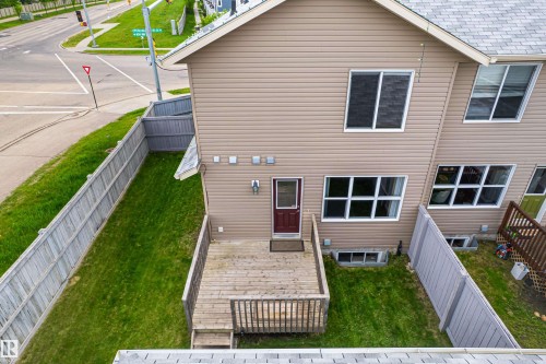 Rear exterior featuring a wooden deck with railing, siding, multiple windows, and a fenced yard - 8204 180 Avenue, Edmonton, AB 
