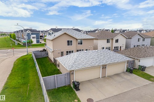Rear exterior featuring a two-story residence with a beige facade, a gray shingled roof, and multiple windows - 8204 180 Avenue, Edmonton, AB 
