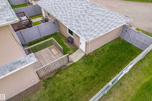 Expansive green space featuring a wooden deck with railing, concrete pathway, and perimeter fencing - 8204 180 Avenue, Edmonton, AB 