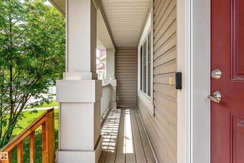 Covered front porch featuring wood-finish flooring, a white column, and a wood railing - 8204 180 Avenue, Edmonton, AB 