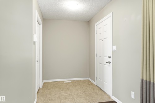 Entryway featuring warm-toned tile flooring, a paneled white door, and neutral wall paint - 8204 180 Avenue, Edmonton, AB 