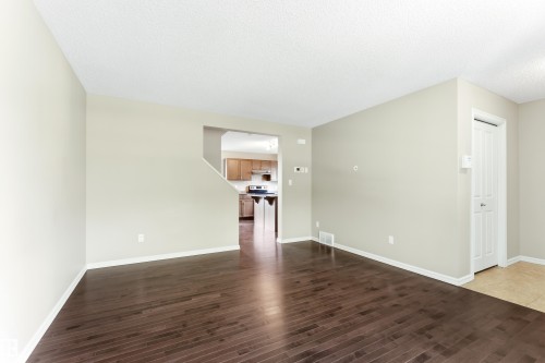 Spacious room with dark wood-finish flooring, light neutral-toned walls, and white trim - 8204 180 Avenue, Edmonton, AB 