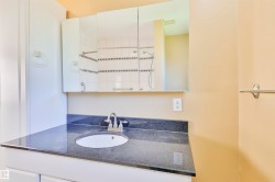 Bathroom vanity featuring a dark stone countertop, undermount sink, and chrome faucet - 