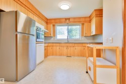 Kitchen featuring wood-finish cabinetry, stainless steel refrigerator, built-in oven, and a single window above the sink - 