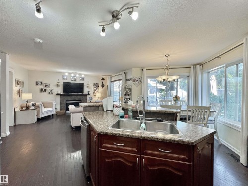 Kitchen island featuring an undermount stainless steel sink and granite-finish countertop - 105 Greystone Crescent, Spruce Grove, AB 