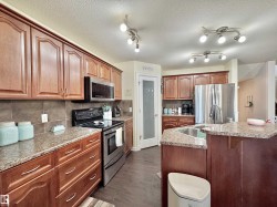 Spacious kitchen featuring warm wood cabinetry, granite countertops, tile backsplash, and stainless steel appliances - 