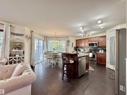 Open-concept kitchen featuring wood-finish flooring, rich wood cabinetry, stainless steel appliances, and an eat-at island - 