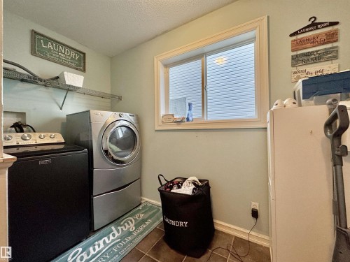 Dedicated utility space featuring a window with blinds, tile-finish flooring, a wall-mounted wire shelf, and light-toned walls - 105 Greystone Crescent, Spruce Grove, AB 