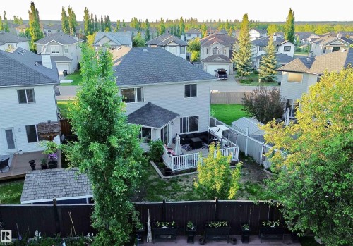 Expansive backyard featuring a wood deck, white railing, and a shaded patio area - 105 Greystone Crescent, Spruce Grove, AB 