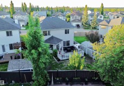 Expansive backyard featuring a wood deck, white railing, and a shaded patio area - 