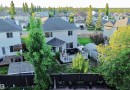 Expansive backyard featuring a wood deck, white railing, and a shaded patio area - 105 Greystone Crescent, Spruce Grove, AB 