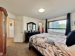 Bedroom featuring a large window with blinds, a ceiling-mounted light fixture, and warm-toned carpeting - 