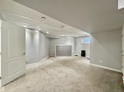 Spacious room featuring light gray walls, plush carpeting, a white paneled door, recessed lighting, and a window providing natural light - 