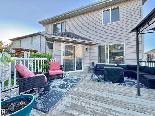 Expansive outdoor deck featuring wood-finish flooring, white picket railing, a sliding glass patio door, and a built-in outdoor lighting fixture - 105 Greystone Crescent, Spruce Grove, AB 