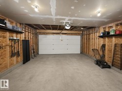 Spacious garage featuring a concrete floor, exposed wood stud walls, and a white overhead door - 