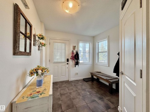 Entryway featuring durable tile flooring, a white paneled door with frosted glass, and multiple windows providing natural illumination - 105 Greystone Crescent, Spruce Grove, AB 