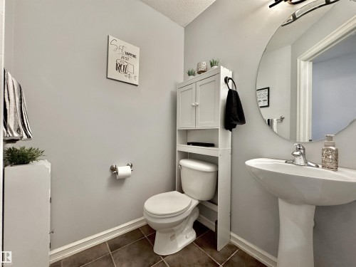 Pedestal sink with chrome faucet and circular mirror - 105 Greystone Crescent, Spruce Grove, AB 