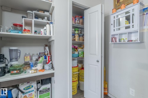Dedicated pantry space featuring built-in shelving, ample storage options, and a paneled door - 107 142 Ebbers Boulevard, Edmonton, AB 