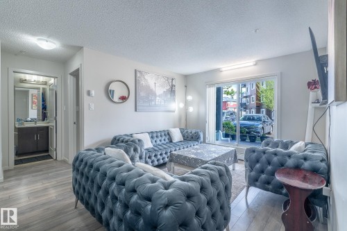 Open living area featuring light wood-finish flooring and a sliding glass door leading to an exterior space - 107 142 Ebbers Boulevard, Edmonton, AB 